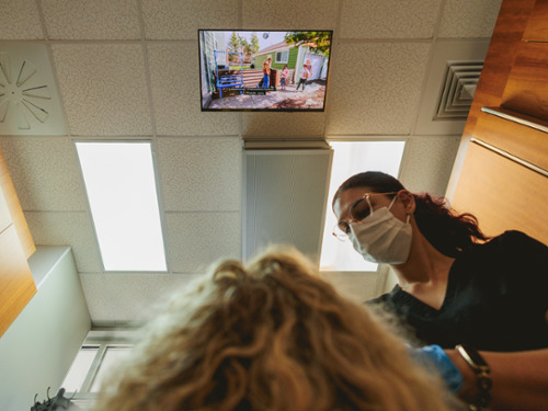 Patient having teeth cleaned while watching TV on ceiling 